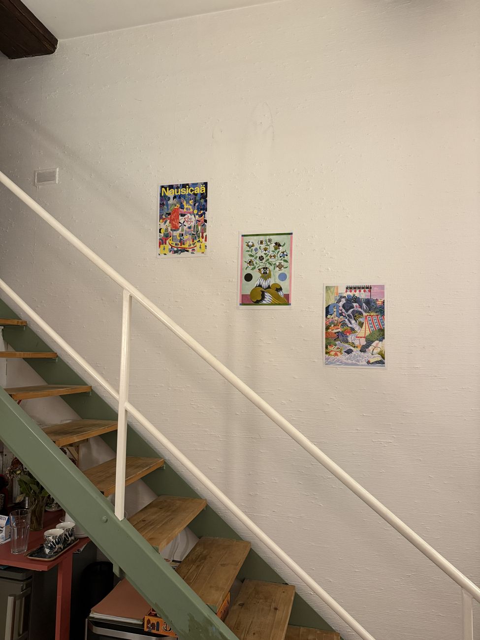 Escalier vert et affiches colorées au mur.
