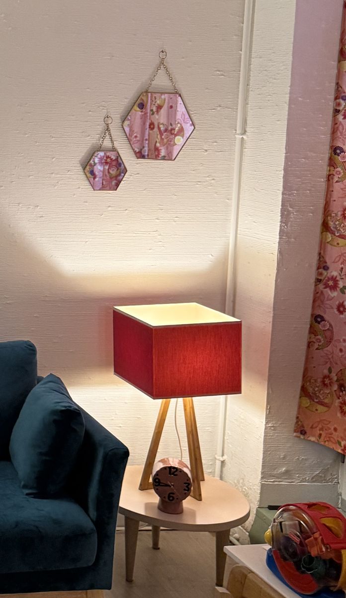 Lampe rouge allumée à côté du canapé bleu.
